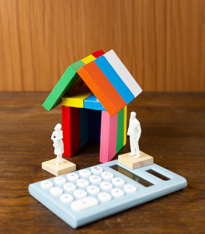 Maquette de maison colorée et calculatrice illustrant une simulation de crédit immobilier